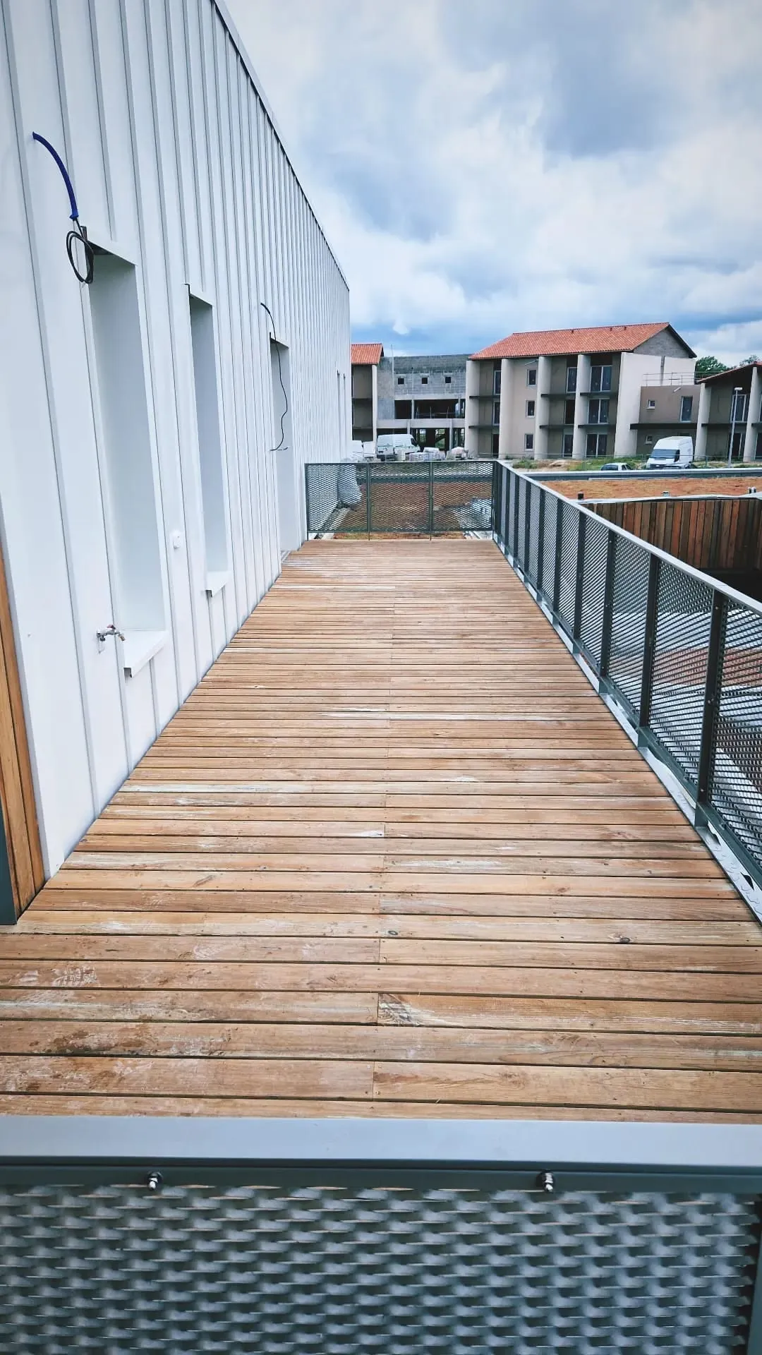 Coursive d’immeuble couverte de lames de bois, avec son garde-corps