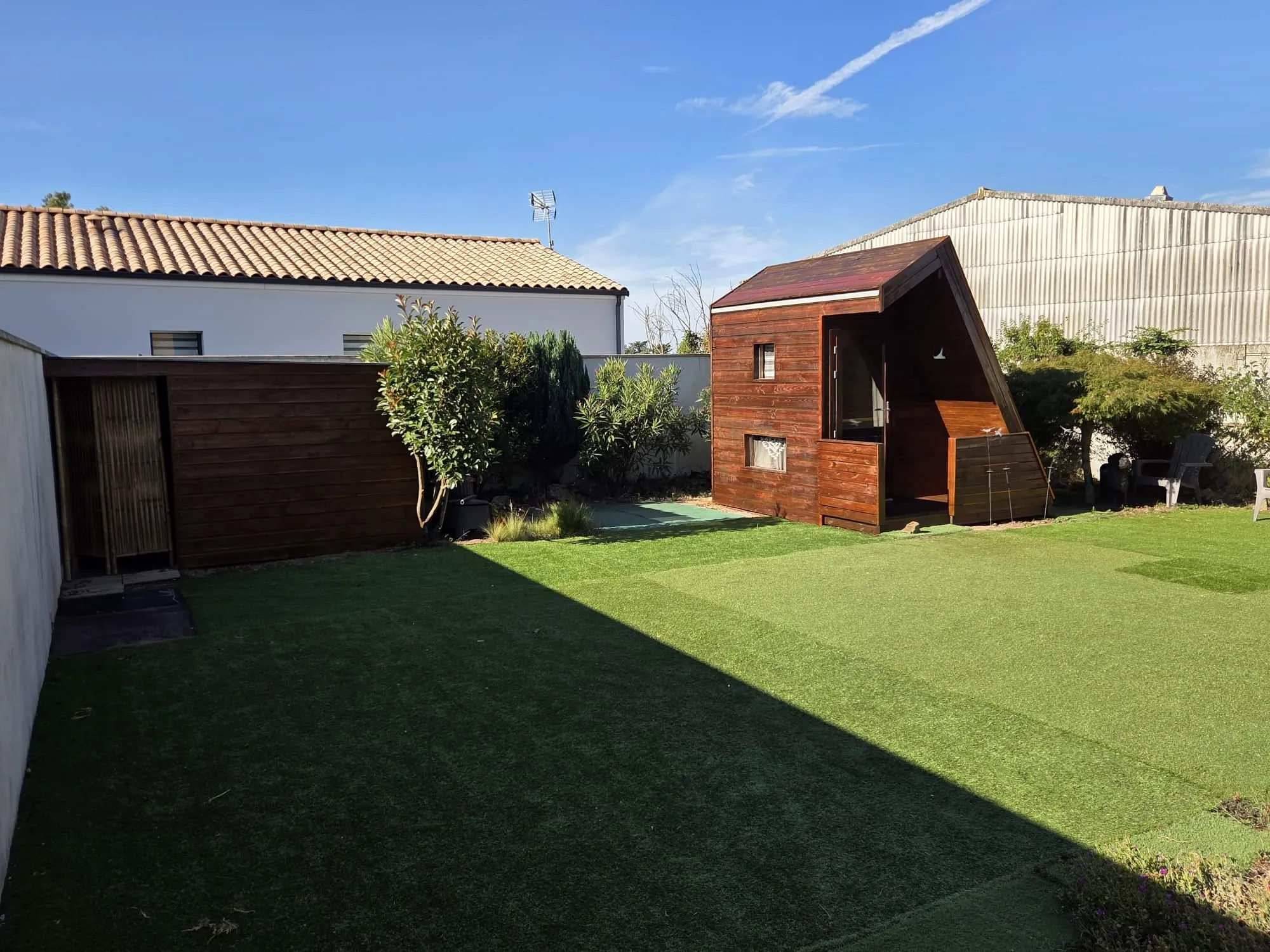 Le même jardin après : abri et cabane en bois teinté sous le soleil