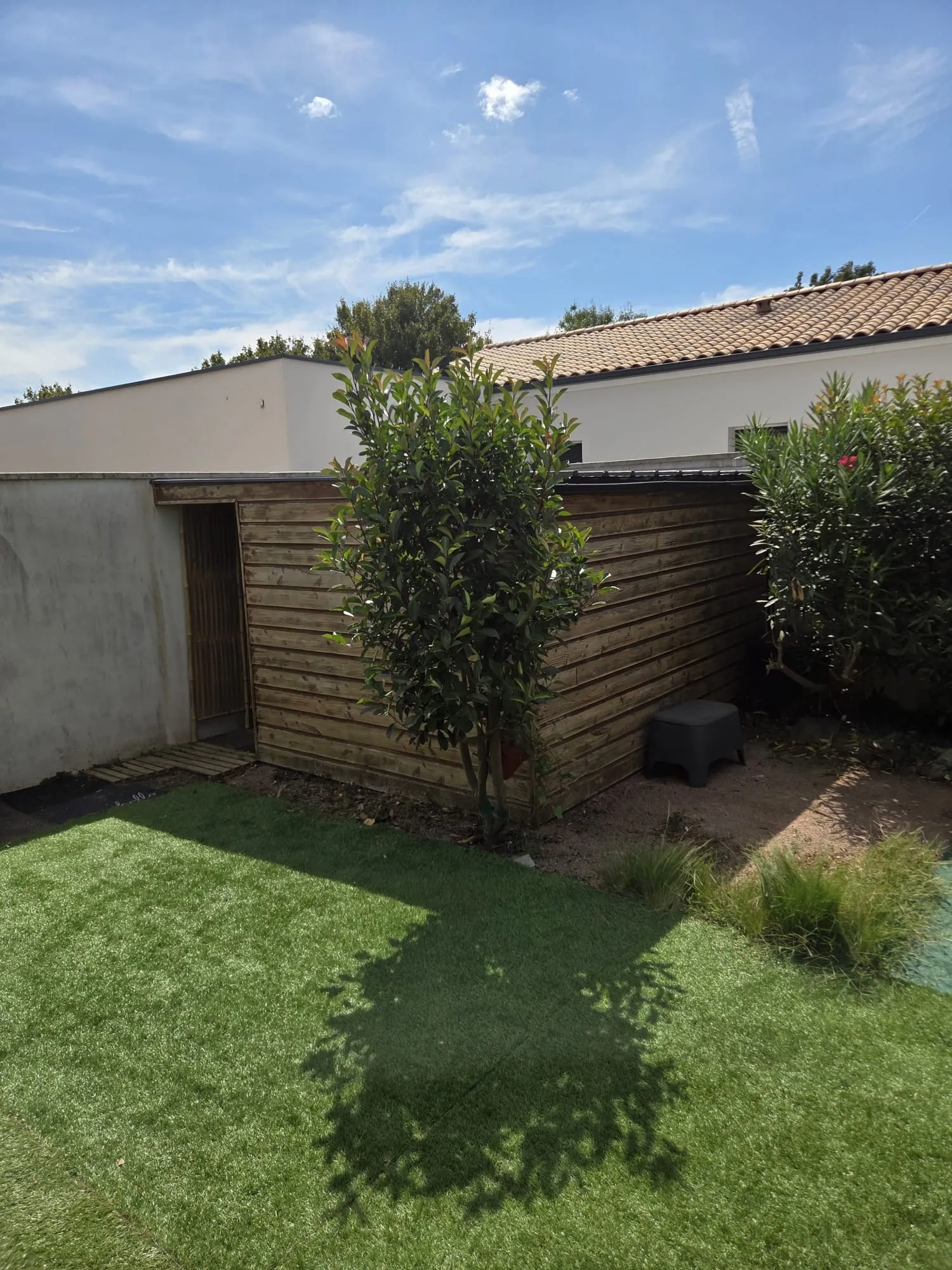 Jardin avant les travaux : abri en bois grisé et murs ternes