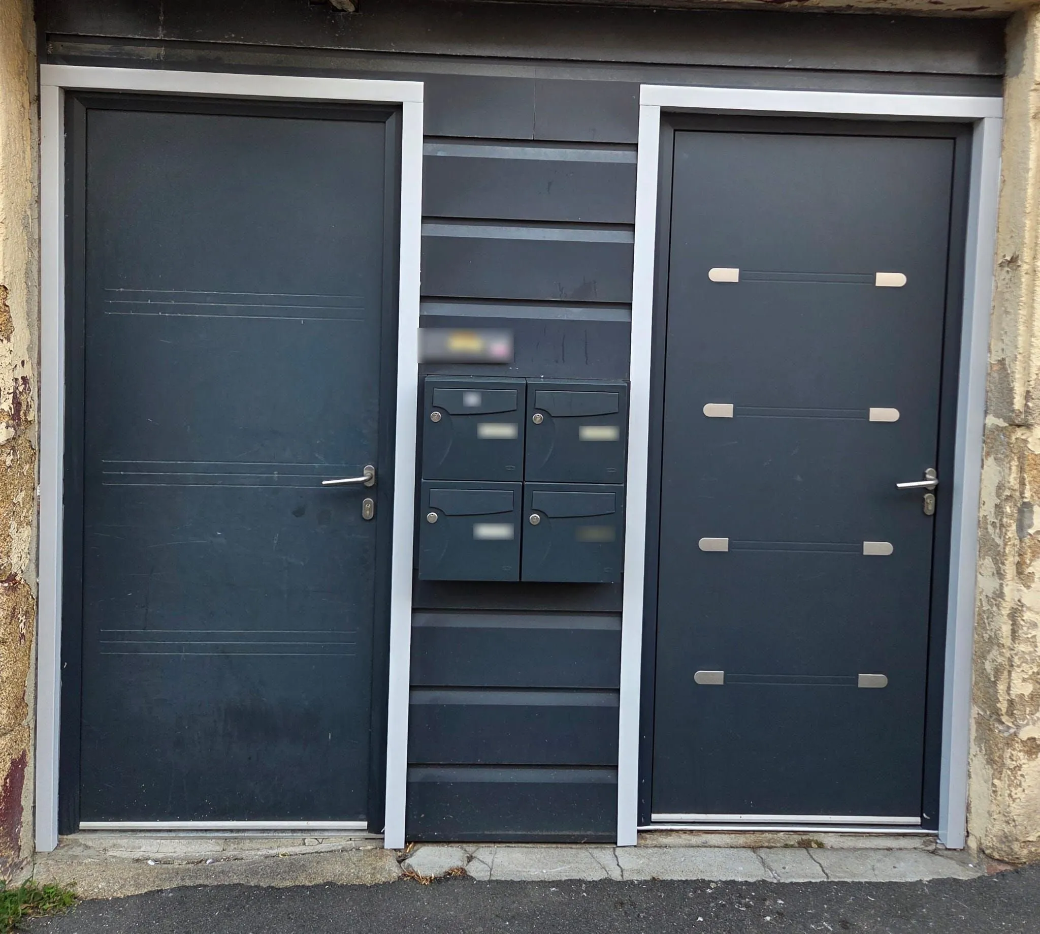 Deux portes d’entrée gris anthracite posées côte à côte, avec les boîtes aux lettres au milieu